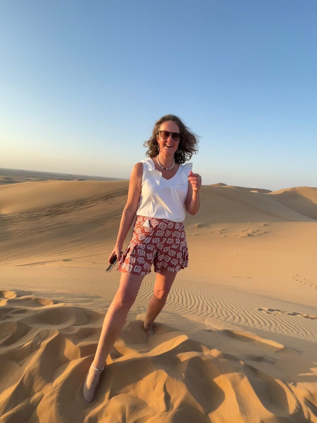 Tanya stood on a sand dune in the desert, blue sky