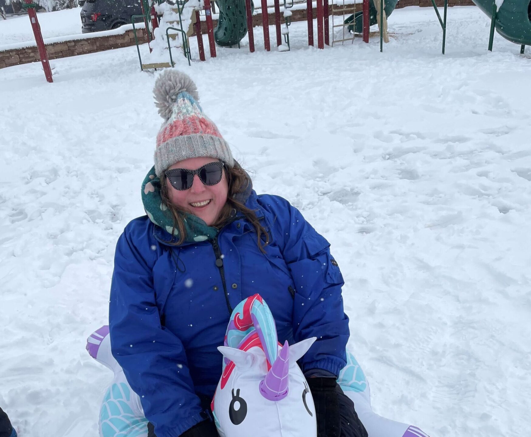 Caroline enjoying sledding in the snow on a blow up unicorn